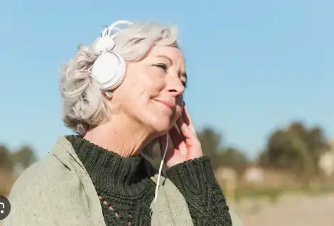 Older woman smiling while listening with headphones outdoors
